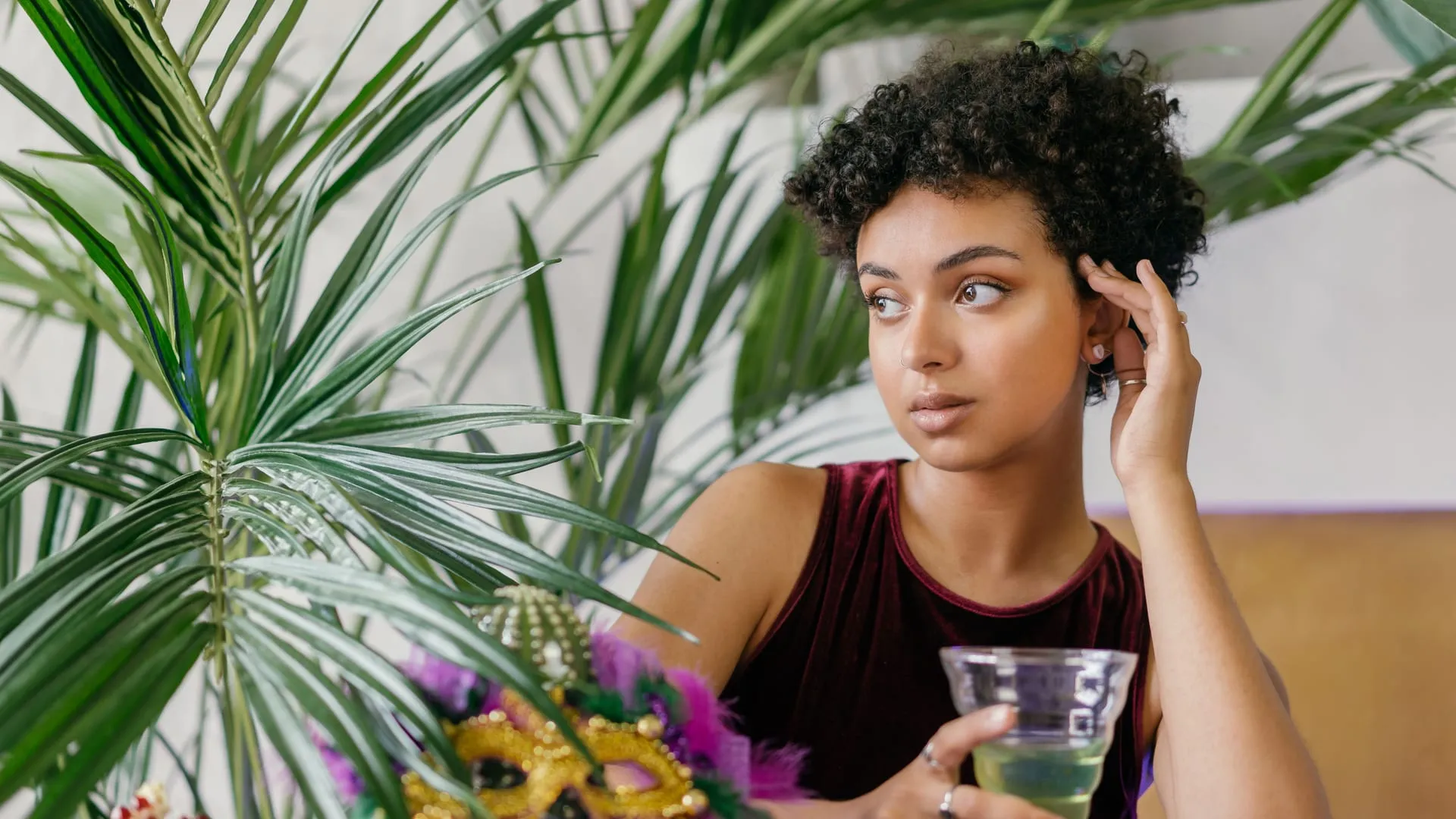 Woman standing quietly at the edge of a party with a drink